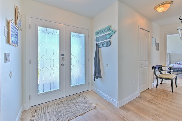 foyer entrance with french doors, light wood-type flooring, and baseboards