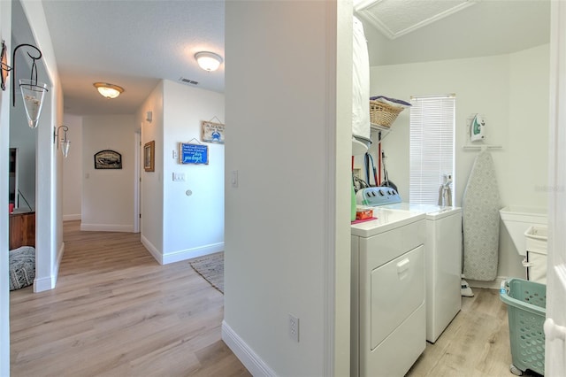 washroom with visible vents, light wood finished floors, baseboards, and washing machine and clothes dryer