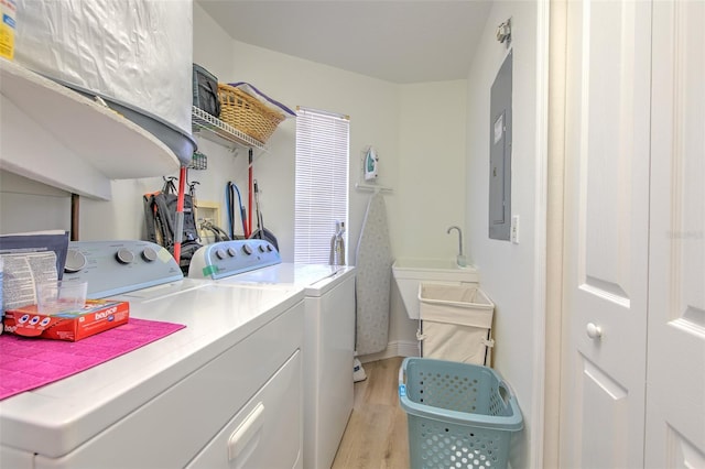 clothes washing area featuring laundry area, washing machine and dryer, light wood-type flooring, and a sink