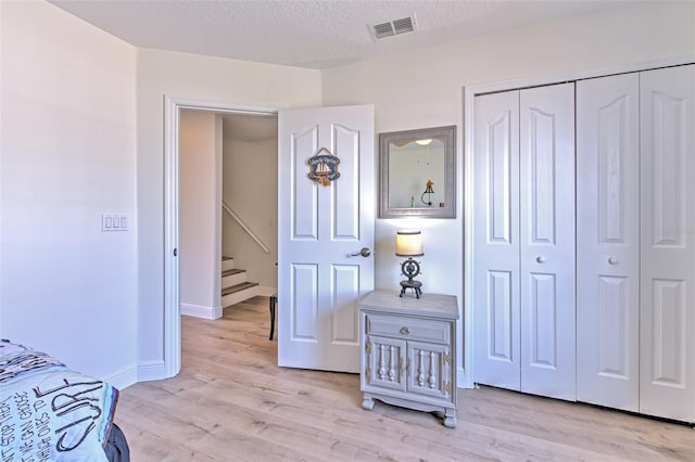 bedroom with visible vents, light wood-style floors, a closet, and a textured ceiling