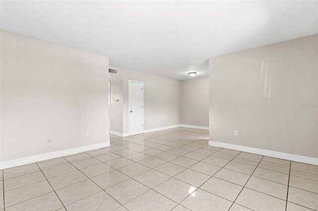 empty room featuring visible vents, baseboards, and light tile patterned floors