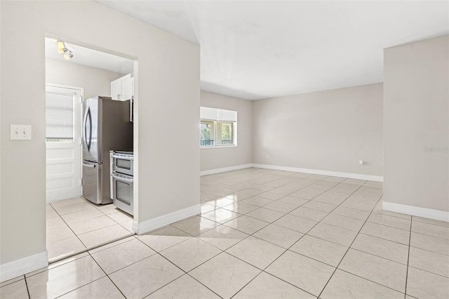 spare room featuring light tile patterned floors and baseboards