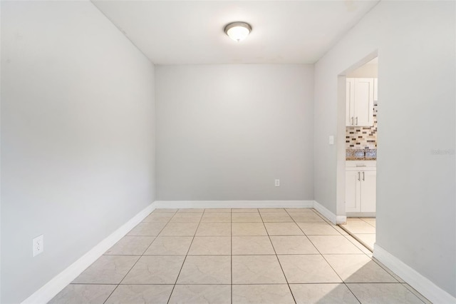 spare room featuring baseboards and light tile patterned flooring