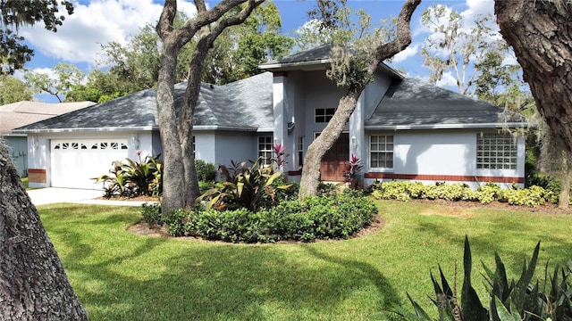 view of front of home featuring a garage, driveway, a shingled roof, a front yard, and stucco siding