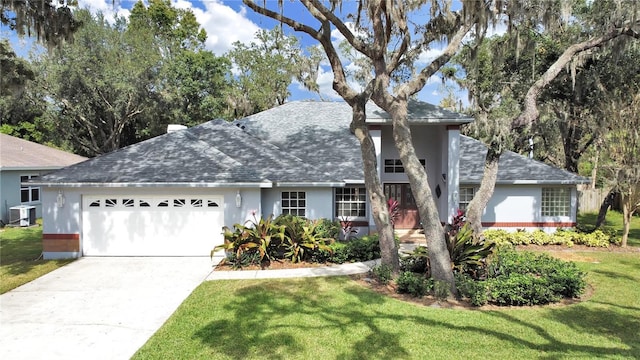 view of front facade with stucco siding, concrete driveway, central AC unit, a front yard, and a garage