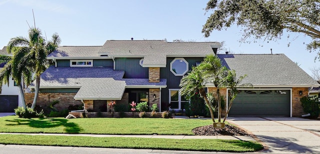 view of front of house with brick siding, a front lawn, concrete driveway, roof with shingles, and a garage