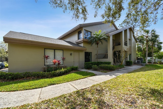 view of front of home with central AC, a front lawn, and stucco siding