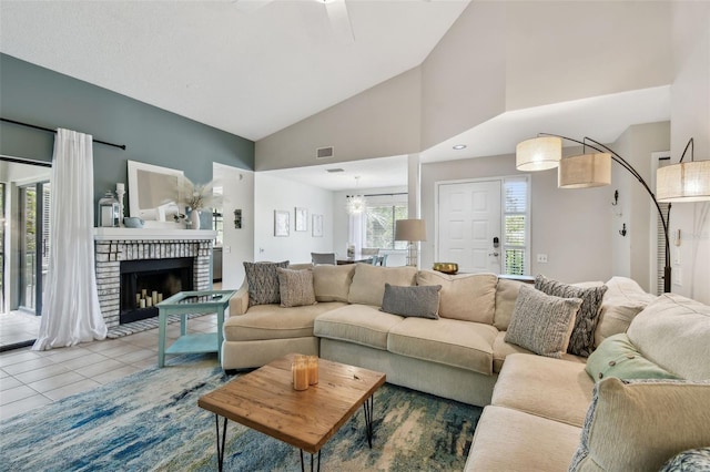 living room featuring high vaulted ceiling, tile patterned flooring, a brick fireplace, and visible vents