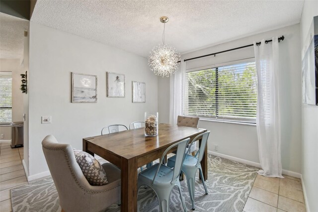 dining space with light tile patterned floors, a textured ceiling, and an inviting chandelier