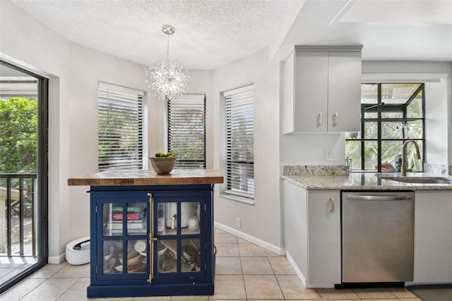 kitchen with pendant lighting, wooden counters, stainless steel dishwasher, a sink, and a textured ceiling