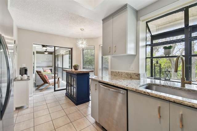 kitchen with a textured ceiling, light tile patterned flooring, butcher block counters, a sink, and appliances with stainless steel finishes