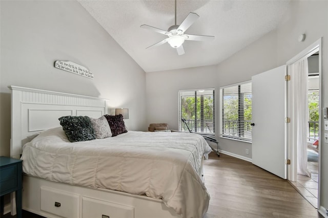 bedroom with ceiling fan, vaulted ceiling, a textured ceiling, wood finished floors, and access to outside