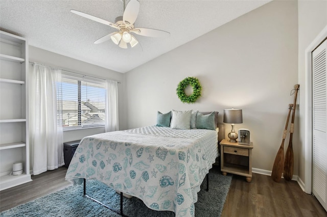 bedroom with ceiling fan, a textured ceiling, wood finished floors, baseboards, and vaulted ceiling