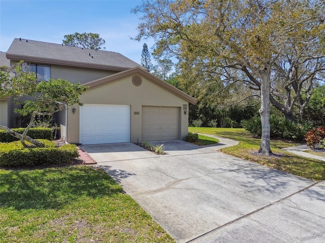 view of front of home featuring concrete driveway, an attached garage, a front lawn, and stucco siding