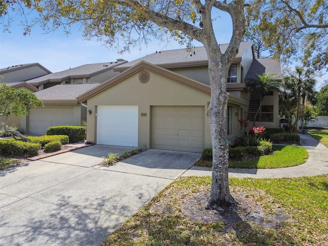 view of property featuring a garage, driveway, and stucco siding