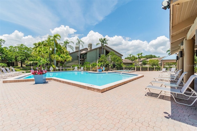 community pool with a patio area and fence