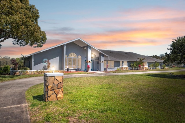 mid-century home with a yard, driveway, and stucco siding