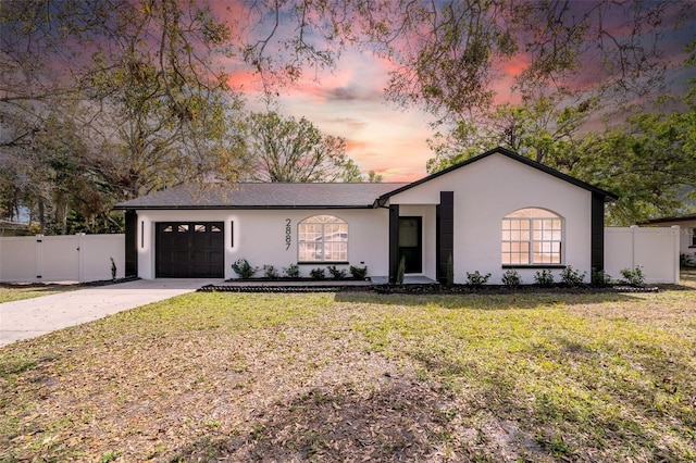 view of front of house featuring stucco siding, driveway, a front yard, and fence