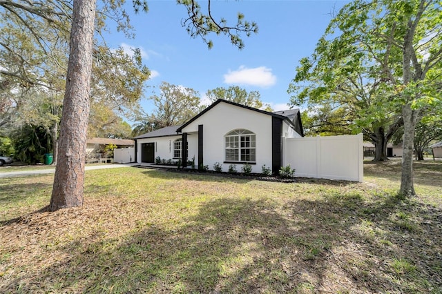 single story home featuring a front lawn, fence, and stucco siding