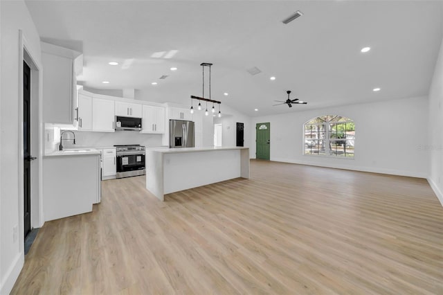 kitchen featuring a center island, open floor plan, light countertops, appliances with stainless steel finishes, and a sink