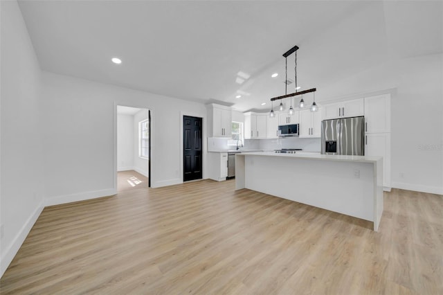 kitchen featuring a center island, appliances with stainless steel finishes, white cabinets, light wood finished floors, and light countertops