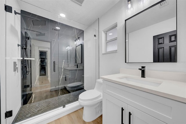 bathroom featuring visible vents, a shower stall, toilet, wood finished floors, and vanity