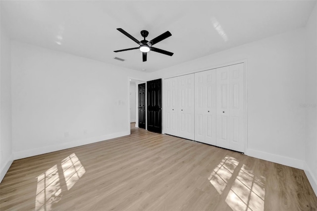 unfurnished bedroom featuring ceiling fan, light wood-style floors, visible vents, and baseboards