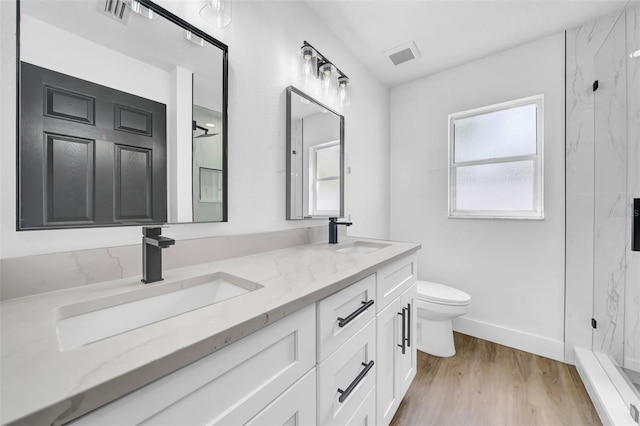 full bath with double vanity, toilet, a marble finish shower, and a sink