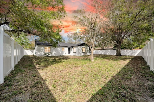 yard at dusk with a fenced backyard