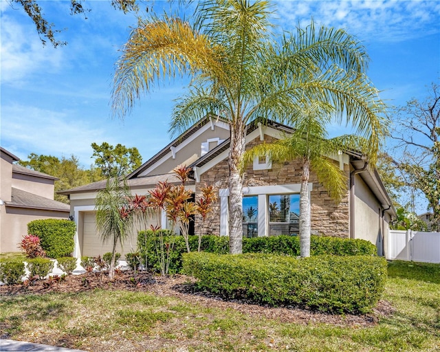 view of front of property with a gate, fence, an attached garage, stucco siding, and stone siding