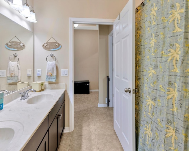 full bath with tile patterned floors, double vanity, baseboards, and a sink