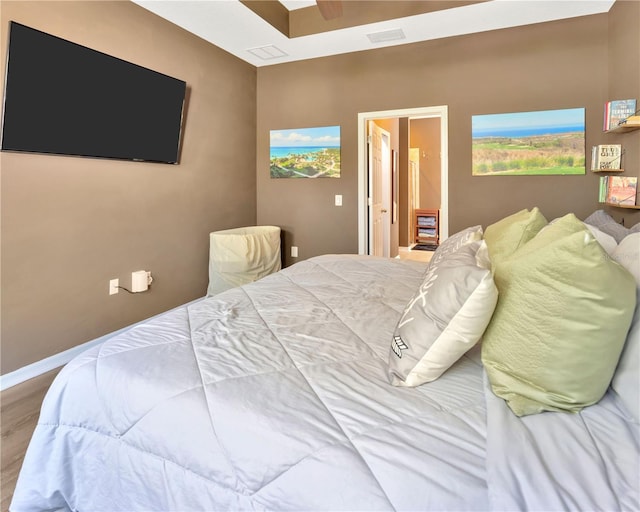 bedroom with visible vents, baseboards, wood finished floors, and a ceiling fan