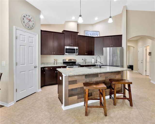 kitchen with high vaulted ceiling, arched walkways, a sink, stainless steel appliances, and dark brown cabinetry