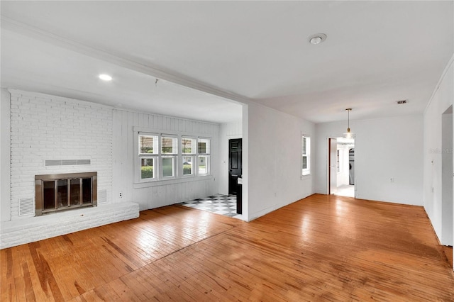 unfurnished living room featuring a fireplace, visible vents, and light wood-style floors