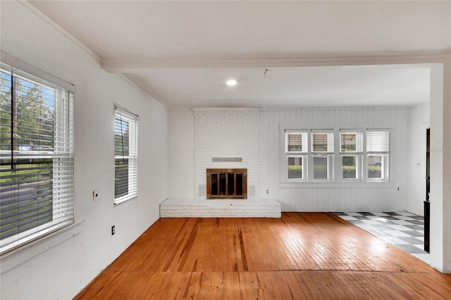 unfurnished living room featuring ornamental molding, a brick fireplace, and hardwood / wood-style flooring