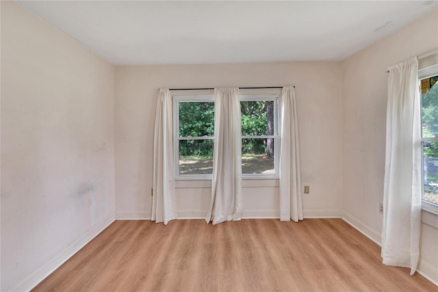 spare room with baseboards and light wood-style floors