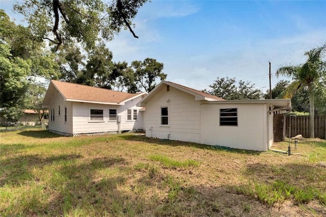 back of house featuring fence and a lawn