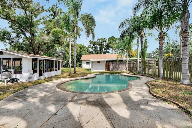 view of pool with a fenced in pool, a sunroom, a patio area, and fence