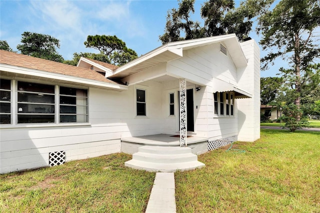 view of front of home featuring roof with shingles, a front lawn, crawl space, and a chimney