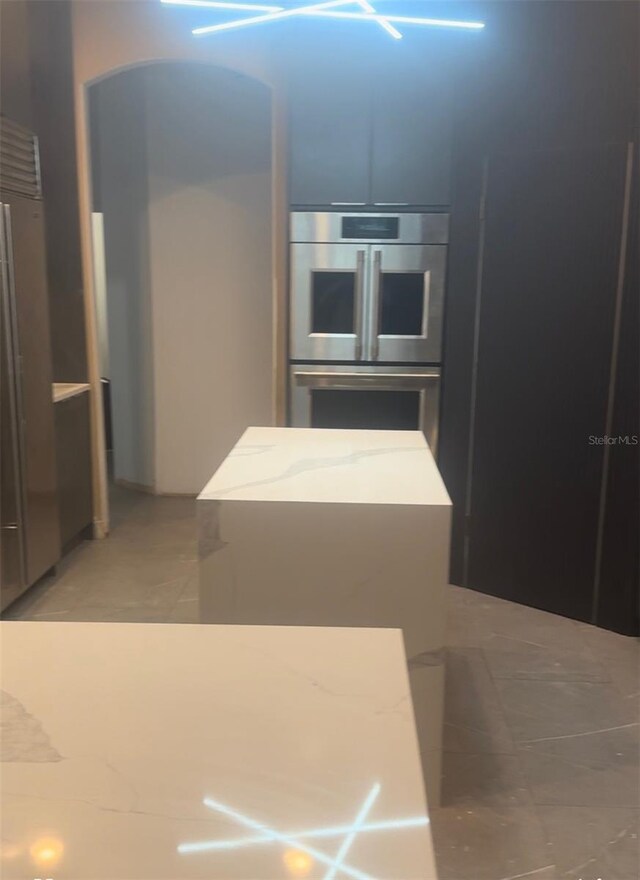 kitchen with light stone countertops, stainless steel refrigerator, and light tile patterned flooring