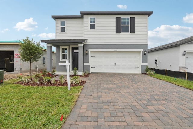 traditional home with decorative driveway, a front yard, an attached garage, and stucco siding