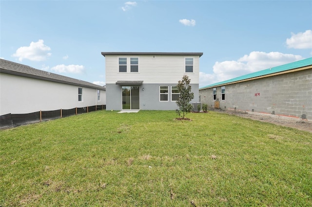 back of house with stucco siding, central AC, a yard, and fence