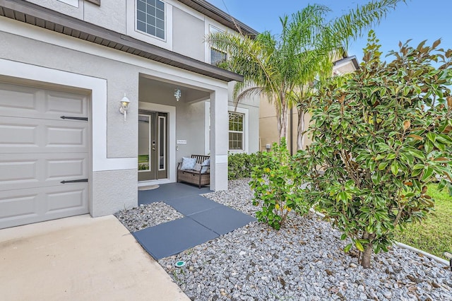 doorway to property with a garage and stucco siding