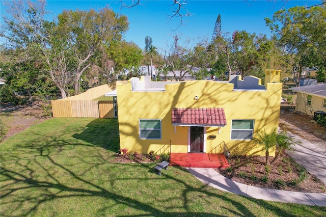 view of front of house with a tiled roof, a front lawn, and stucco siding