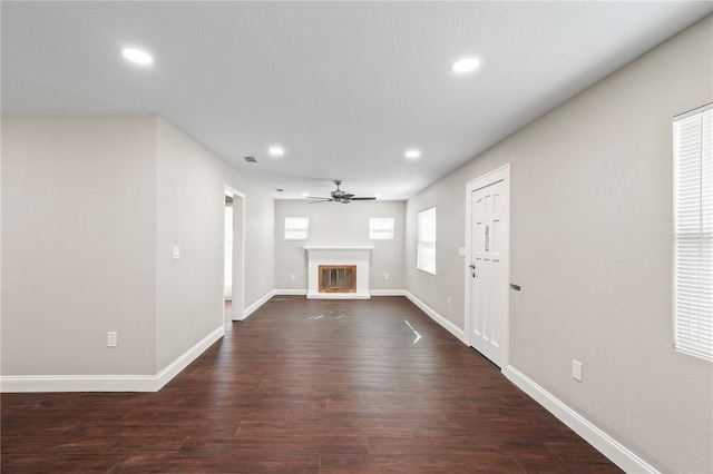 unfurnished living room featuring a glass covered fireplace, dark wood-style flooring, and recessed lighting