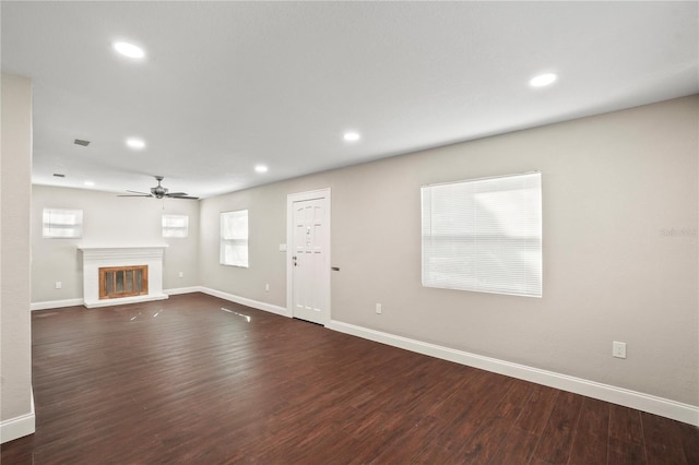 unfurnished living room with dark wood-type flooring, a glass covered fireplace, and recessed lighting