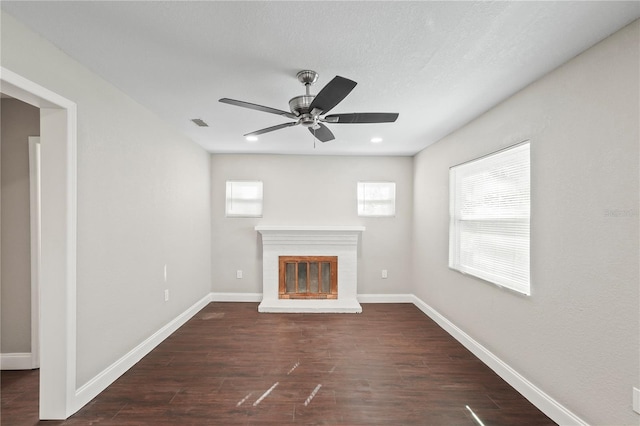 unfurnished living room featuring dark wood-type flooring, a brick fireplace, and baseboards