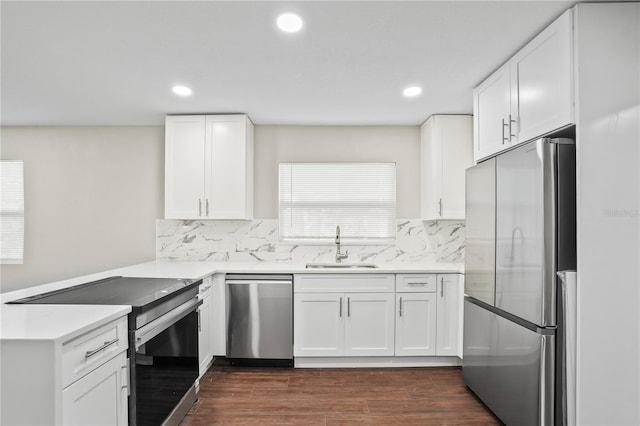 kitchen featuring appliances with stainless steel finishes, dark wood-style flooring, a peninsula, light countertops, and a sink