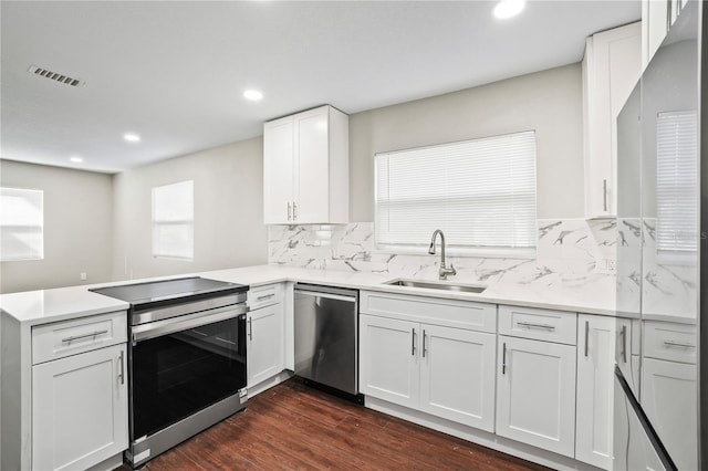 kitchen featuring white cabinets, a peninsula, a sink, stainless steel appliances, and backsplash