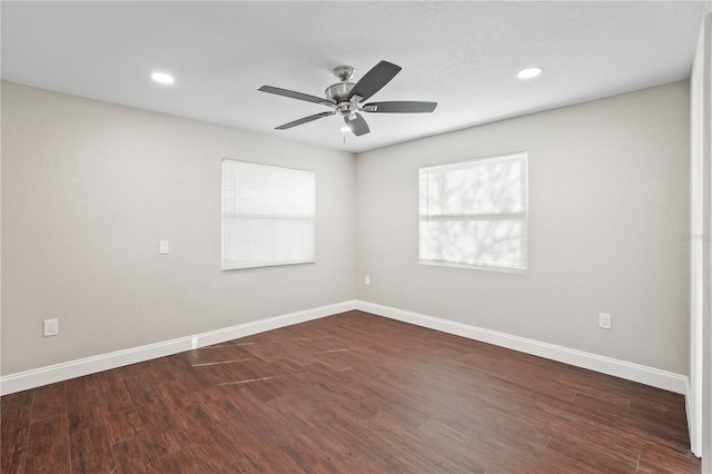 unfurnished room with dark wood-style flooring, a ceiling fan, and baseboards